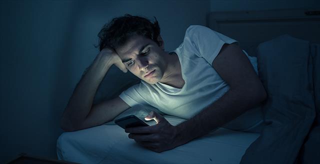 man staring at his smartphone in dark