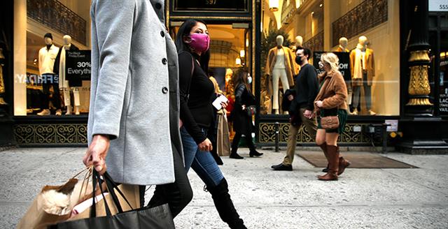 people walking on a city sidewalk in front of clothing storefront
