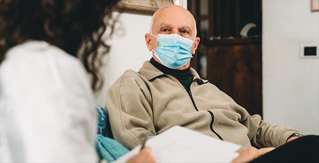 older gentleman in a non medical mask speaking with a medical professional