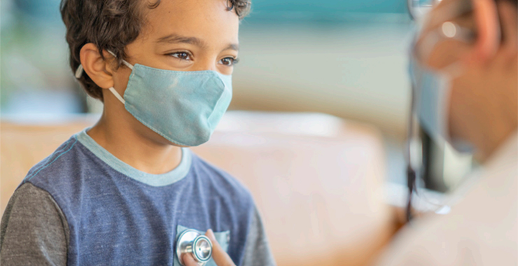 medical professional with a stethoscope listing to the heart of a young boy
