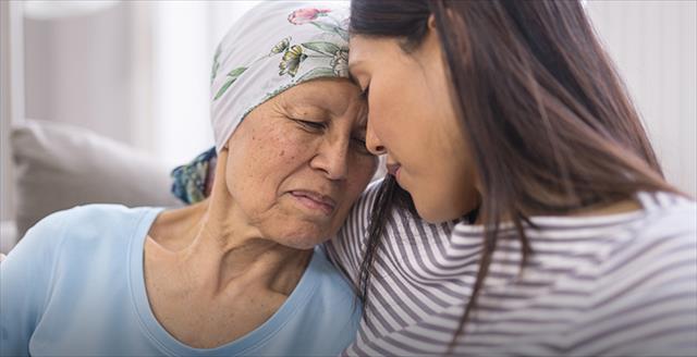 younger woman comforting an older woman wearing a head scarf