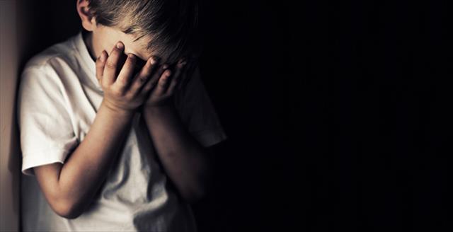 young boy with his hands over his face
