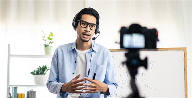 man wearing a headset speaking in front of a camera