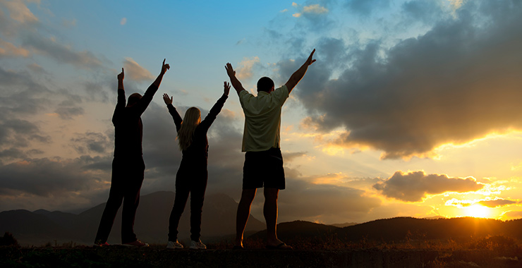 three people standing outside with their arm raised into the air