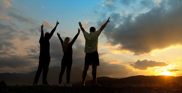 three people standing outside with their arm raised into the air