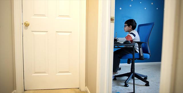 boy sitting in front of a laptop in his bedroom