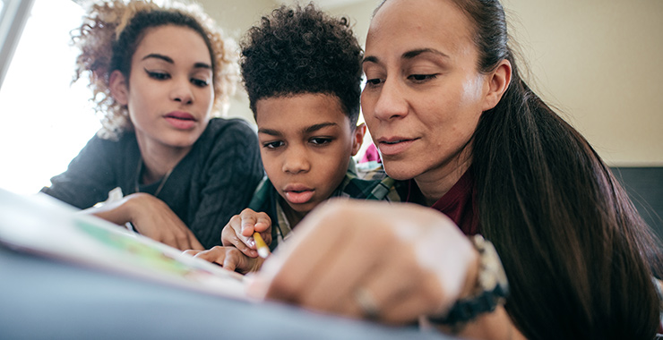kids looking at a book with their mother