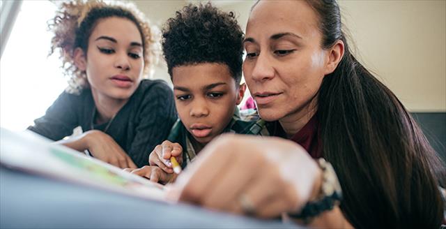 kids looking at a book with their mother