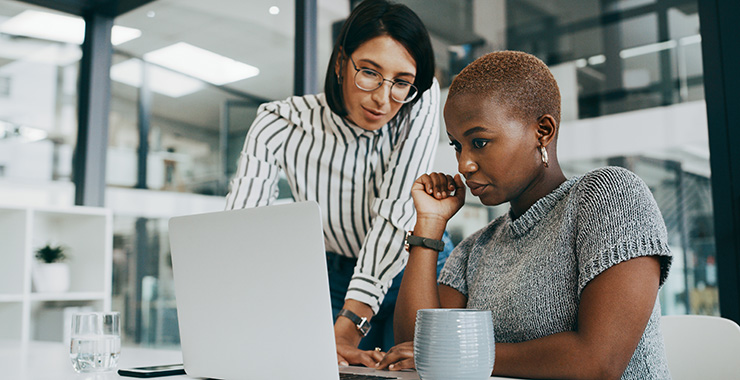 two women discussing something in front of a computer