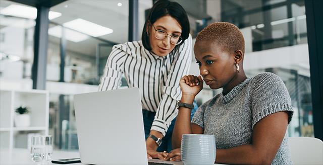 two women discussing something in front of a computer