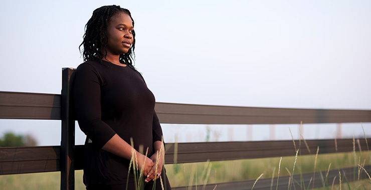 woman of color leaning against a wood fence
