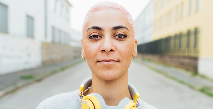 young woman with short pink hair wearing headphones
