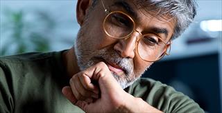 older man with glasses sitting alone