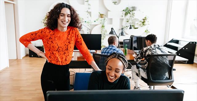 two women standing by a desk in an office