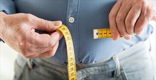 man putting a measuring tape around his waist