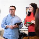 Man with educator smiling in front of a classroom