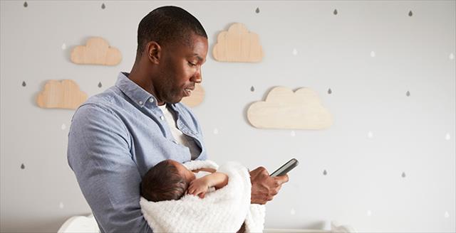 man holding a baby and looking at a smartphone