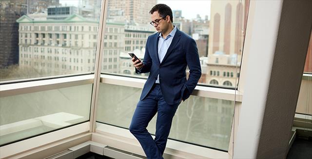 man in a suit looking down at a smartphone