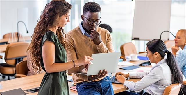 a man and a woman looking at something on a laptop together
