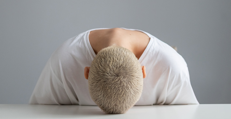 person sitting with their head down on a table
