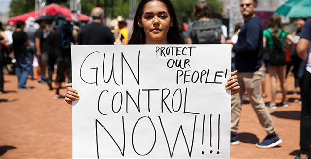 woman holding a hand written gun control sign