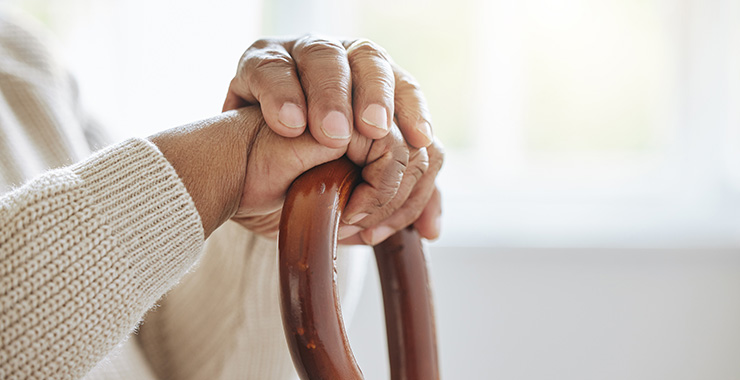 hands resting on a wooden cane