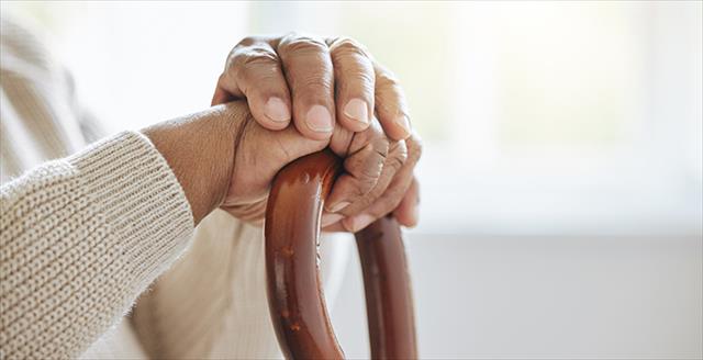 hands resting on a wooden cane