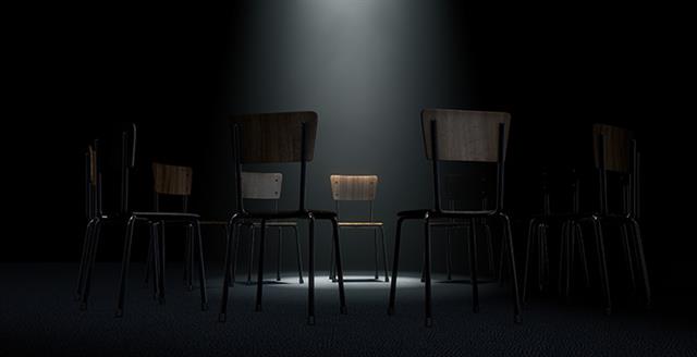 small chair under a spotlight in a dark room