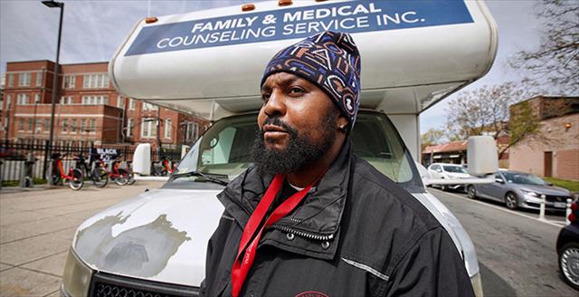 man standing in front of a mobile counseling service van