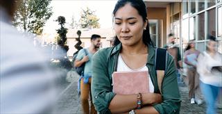 college student looking distressed while clutching textbooks