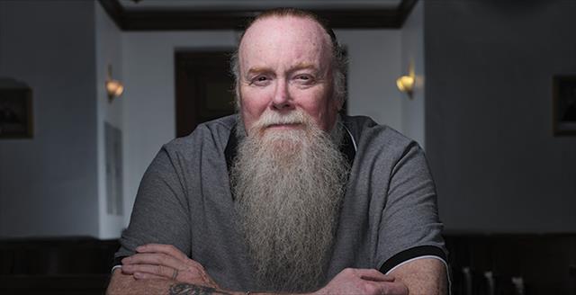 man with long beard sitting in a prison visiting room