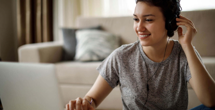 Young woman using laptop and listening to music at home