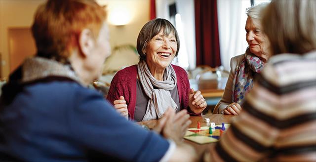 group of older women sitting around a table playing a board game