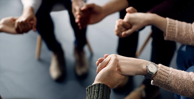 people holding hands while sitting chairs in a circle
