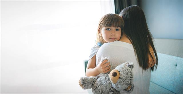 woman holding a small girl who is holding a stuffed animal