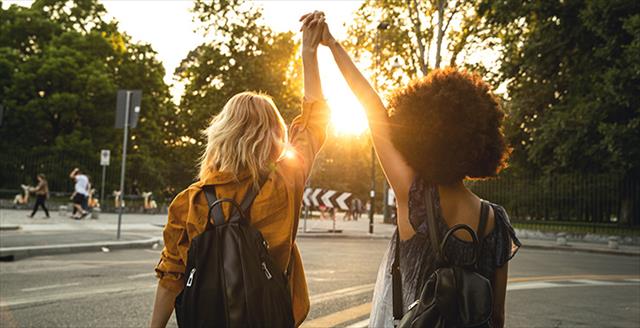 two women holding hands with arms held over their heads 