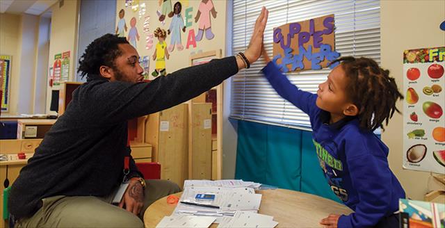 male teacher giving a young male student a high five