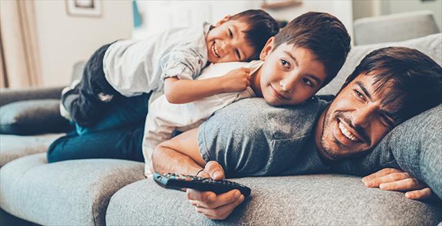 father on a couch with two young sons