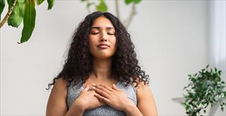 woman standing with her eyes closed and hands crossed over her chest