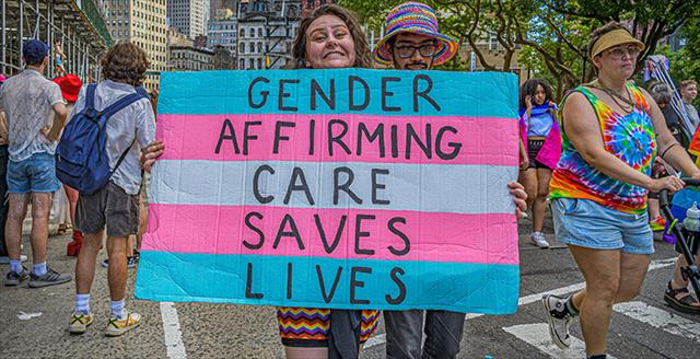 woman holding a sign supporting gender affirming care