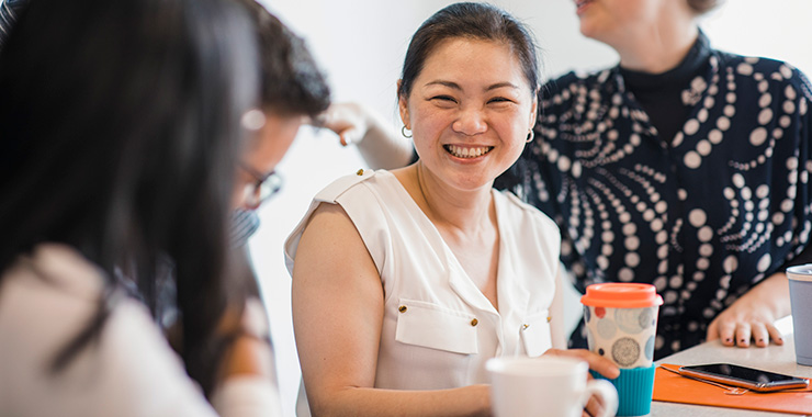 seated woman smiling and holding a travel coffee mug
