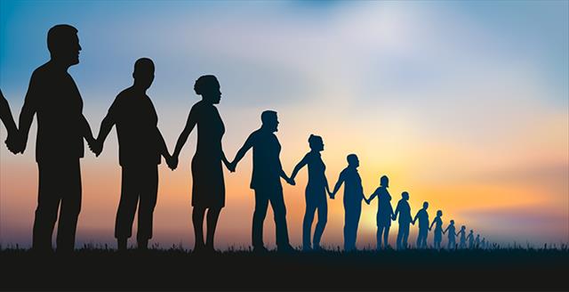 silhouettes of people holding hands in a long line at sunset