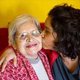 younger woman giving an older woman a kiss on the cheek