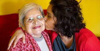 younger woman giving an older woman a kiss on the cheek