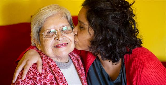 younger woman giving an older woman a kiss on the cheek