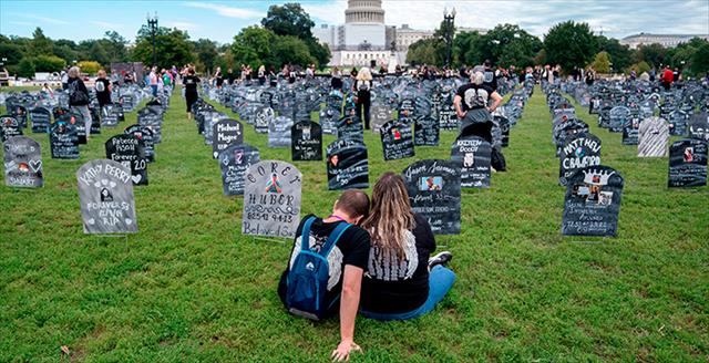 people walking through a display of representative headstones