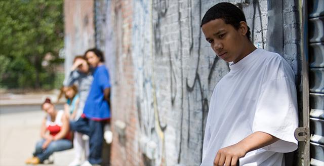 people hanging out in front of a brick wall painted with grafitti