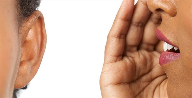 close up of person with hand by mouth about to whisper something