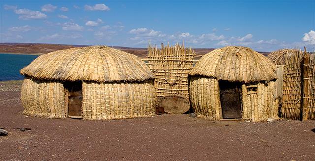 indigenous huts next to a body of water