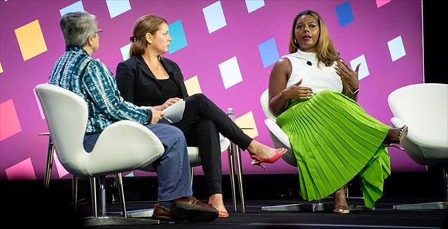 woman having a discussion on a stage with other presenters